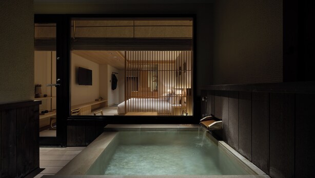 Un bain traditionnel de style japonais, avec un intérieur en bois et une vue sur une partie de la chambre.