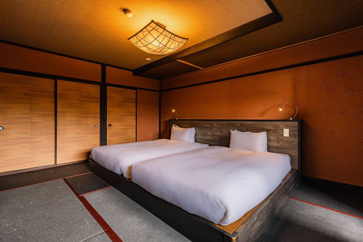 Una habitación con dos camas, cabecero de madera, lámpara en el techo y una pared con textura.