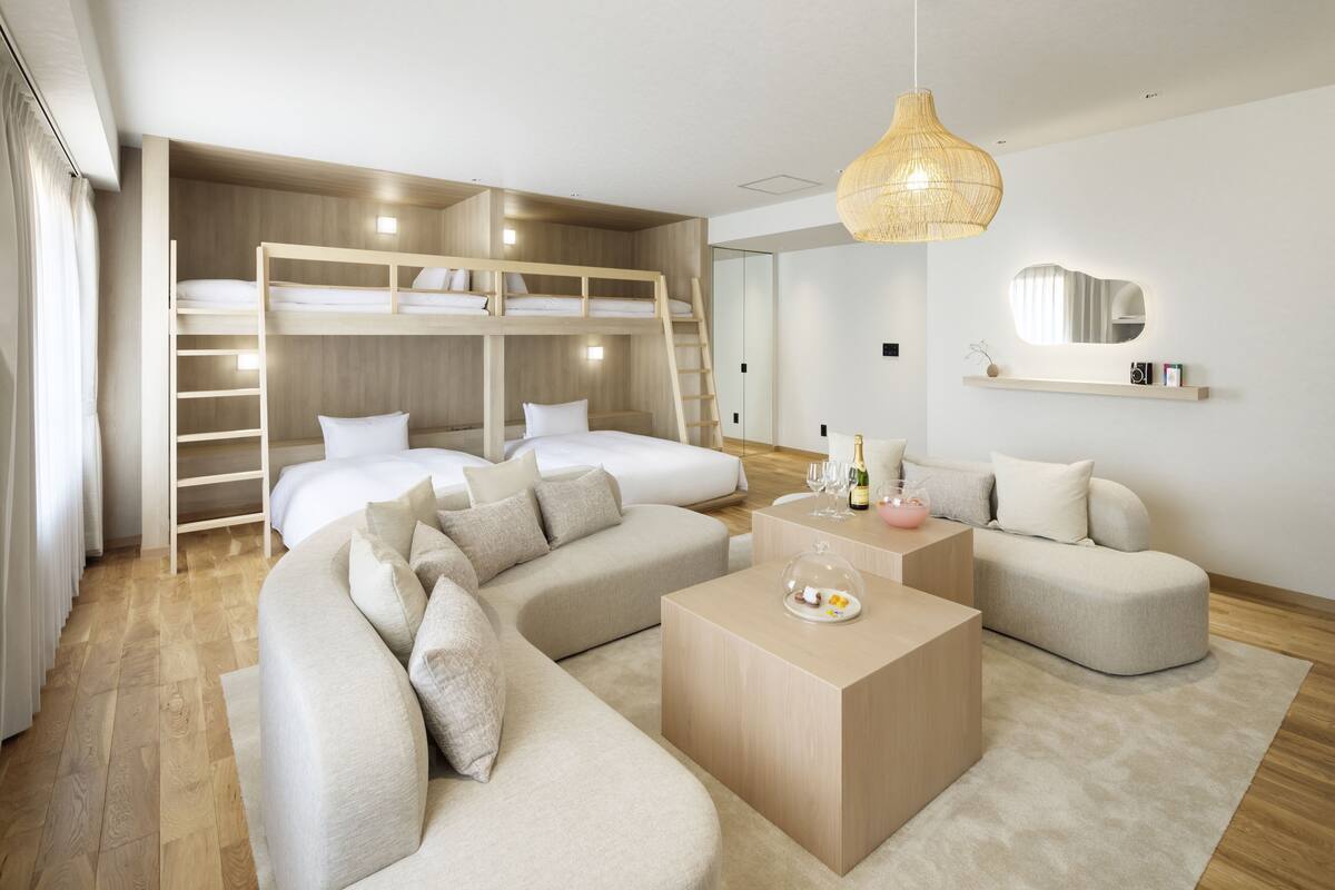Un dormitorio moderno con literas, un sofá, una mesa de centro y un espejo.