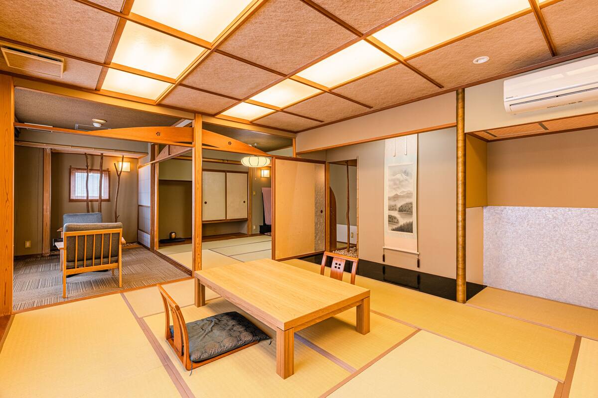 Una habitación japonesa tradicional con suelo de tatami, una mesa baja y una puerta corredera.