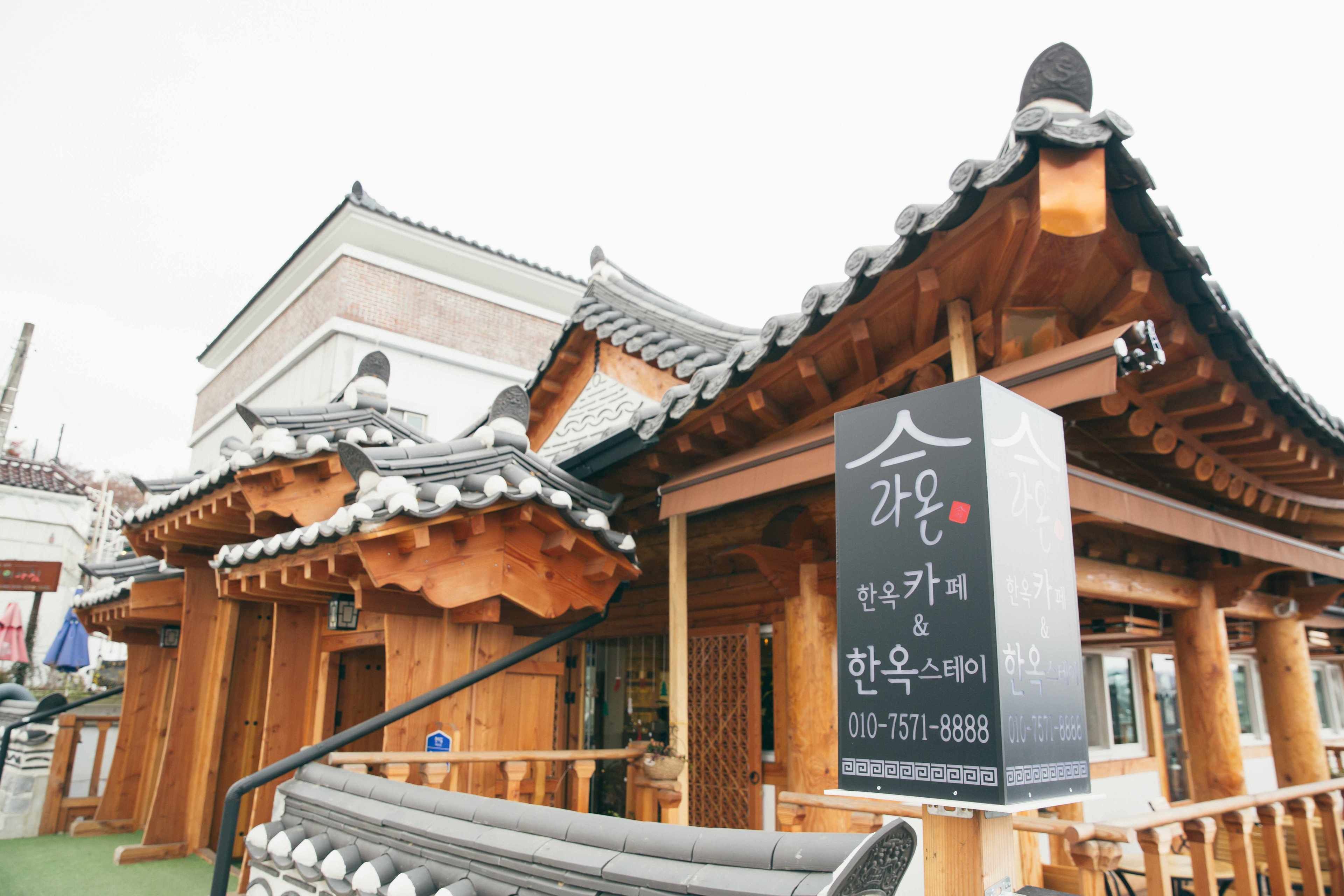 A traditional Korean wooden building with a signboard displaying contact information.