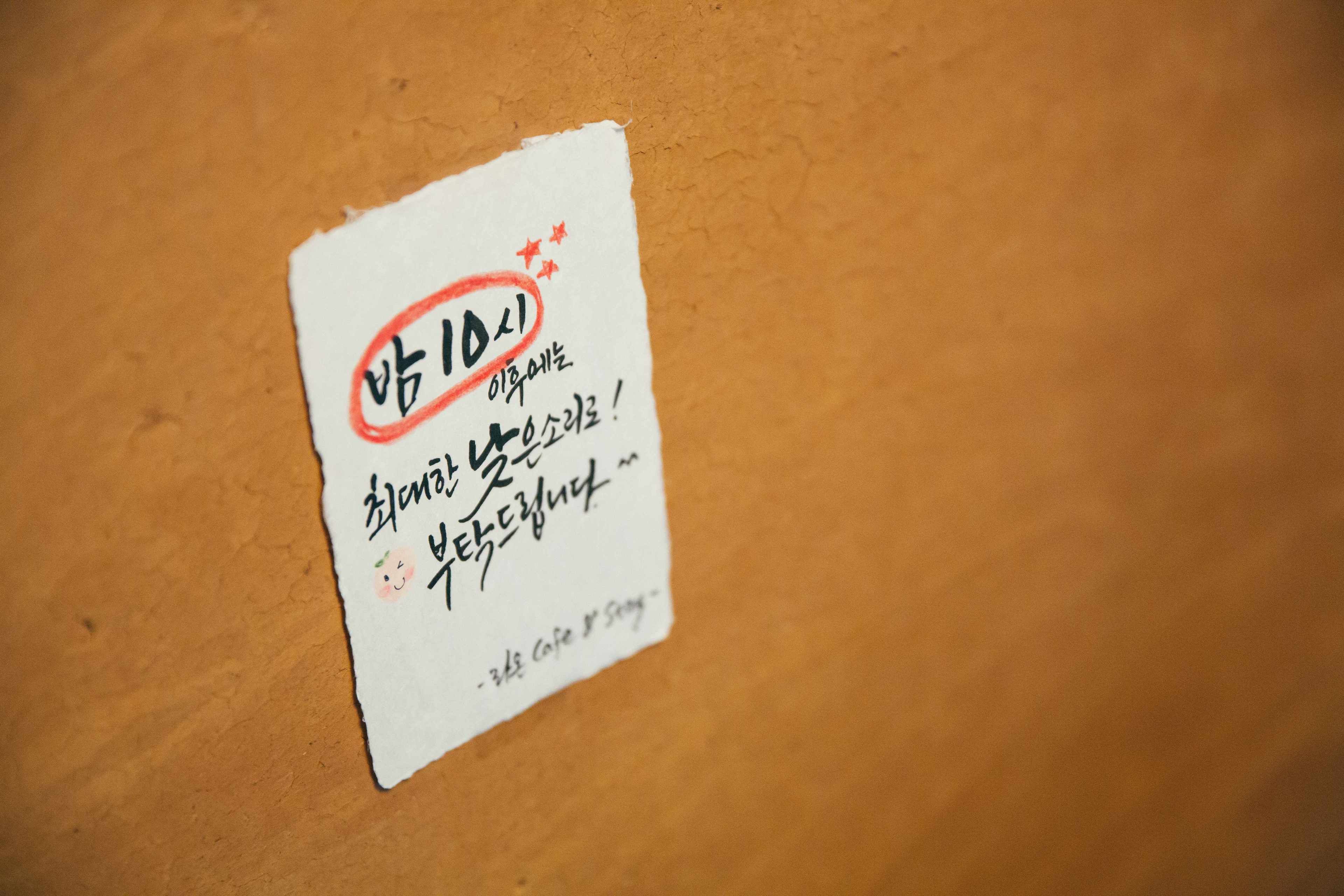 A piece of paper with Korean text and a small drawing of a smiling face.