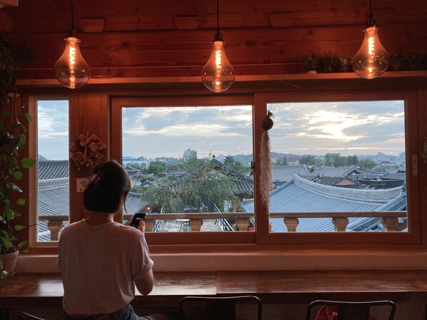 Una persona tomando una foto a través de un ventanal con vistas a una arquitectura tradicional y un paisaje urbano.