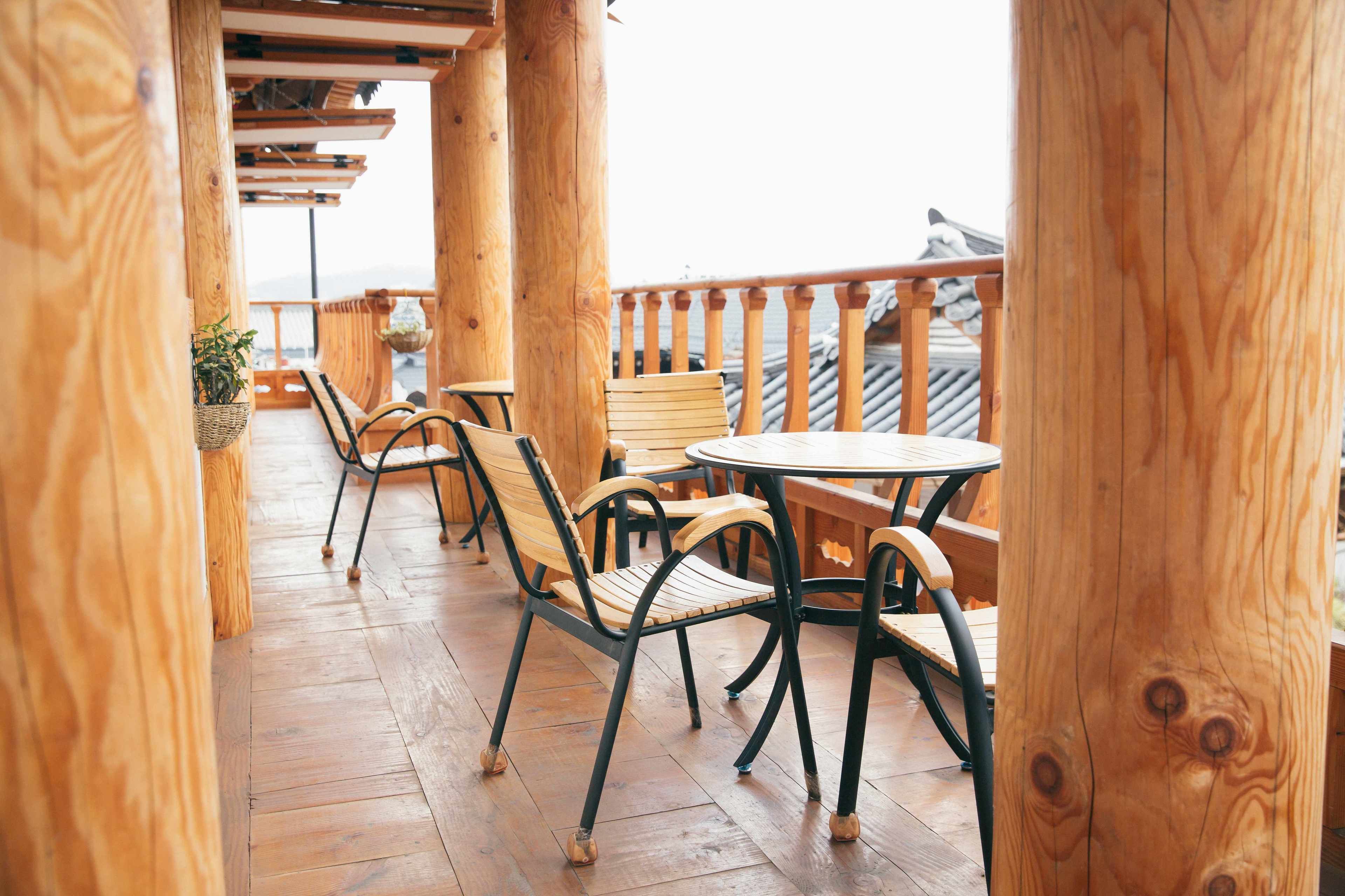 A wooden deck with outdoor seating, including chairs and a table.