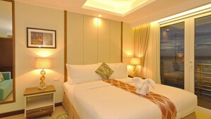 A hotel room with a large bed, two bedside lamps, a framed artwork on the wall, and a view through the glass door. - Belian Hotel (Tagbilaran)