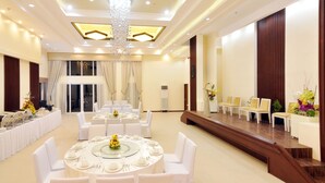 A spacious banquet hall with round tables set for dining, a stage for presentations, and a chandelier. - Belian Hotel (Tagbilaran)