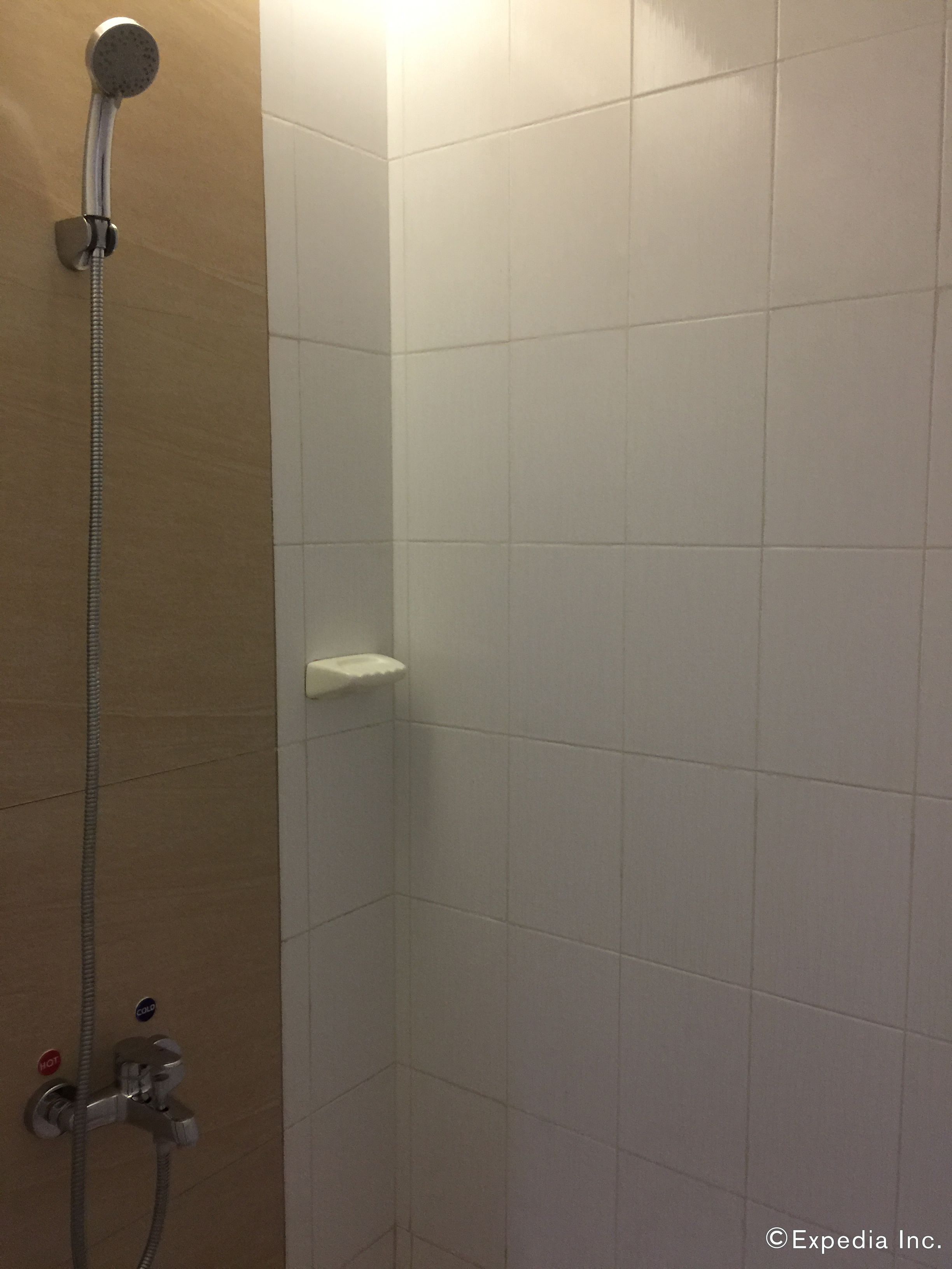 A shower with a handheld showerhead and a wall-mounted faucet.