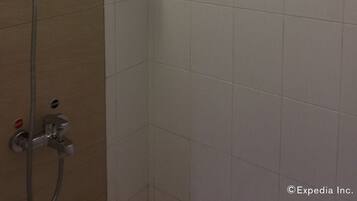 A shower with a handheld showerhead and a wall-mounted faucet.