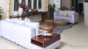 A modern living room with a white sofa, a wooden coffee table, and a hanging light fixture. There are wall-mounted artworks and potted plants. - Belian Hotel (Tagbilaran)