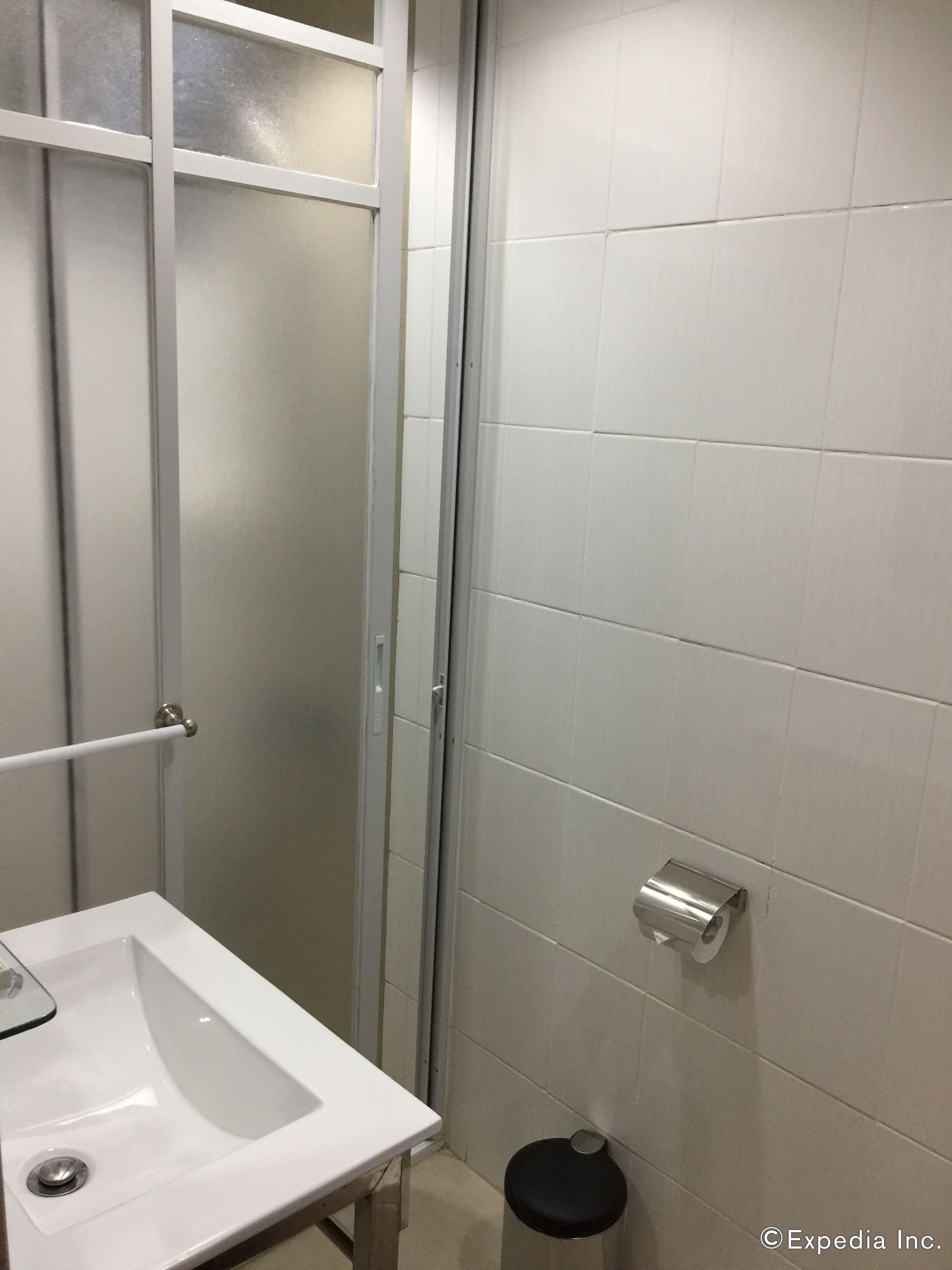 A bathroom with a white sink, a glass shower enclosure, and a toilet paper holder on the wall.