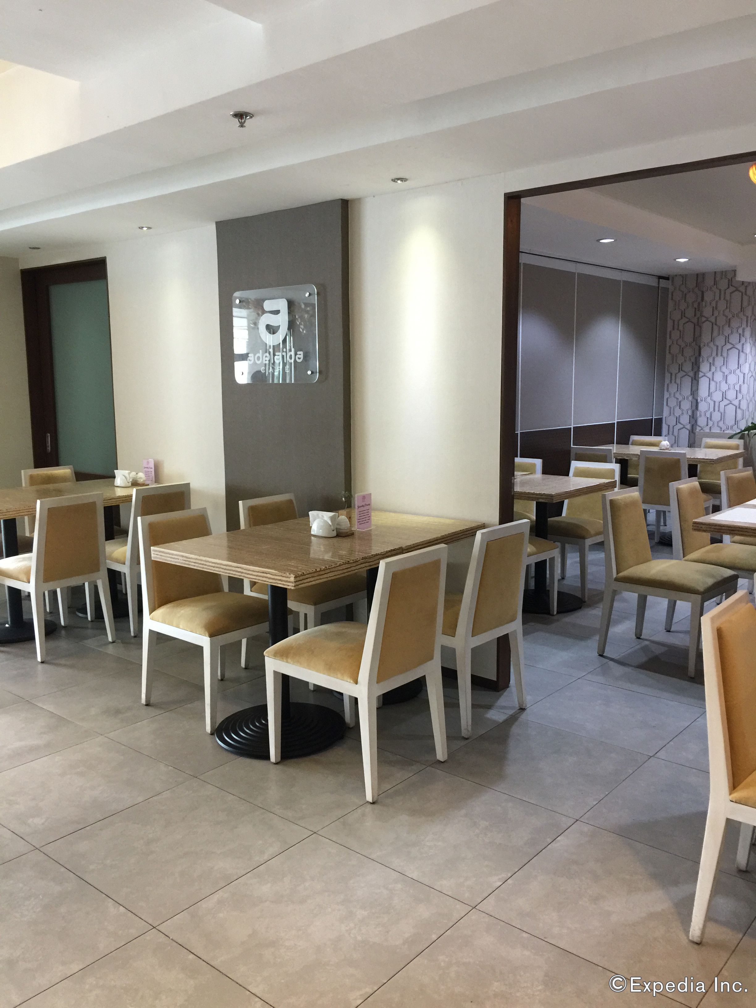 A modern dining area with multiple tables and chairs, a sign indicating a restaurant, and a patterned wall.