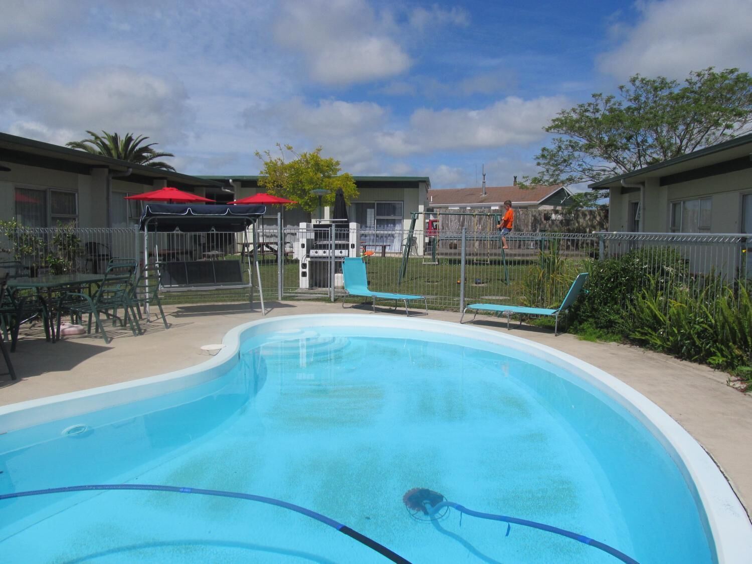 A swimming pool with lounge chairs and a barbecue area.