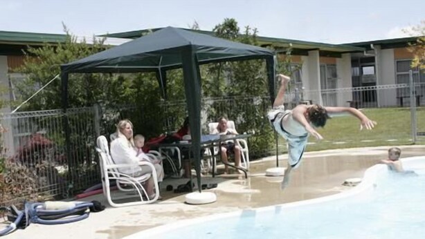 A pool area with a diving platform, lounge chairs, and a covered seating area. - Parkview Motel (Dargaville)