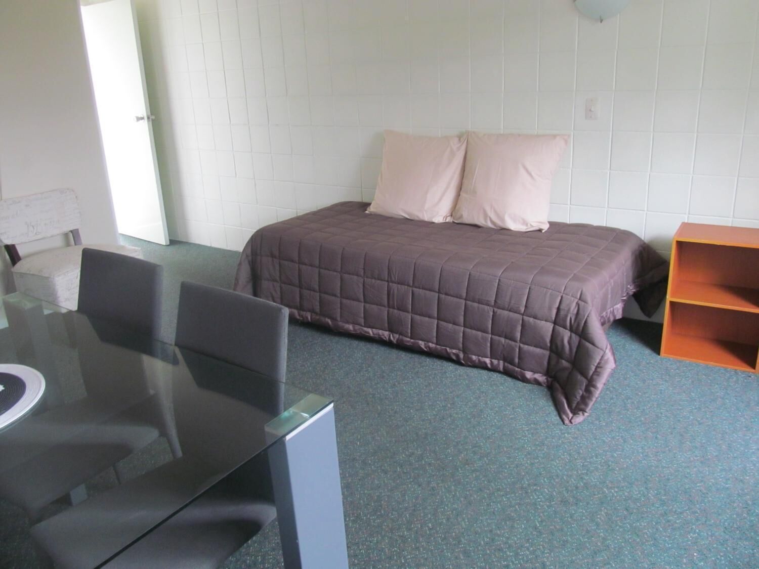 A bedroom with a bed, a desk, and a chair.