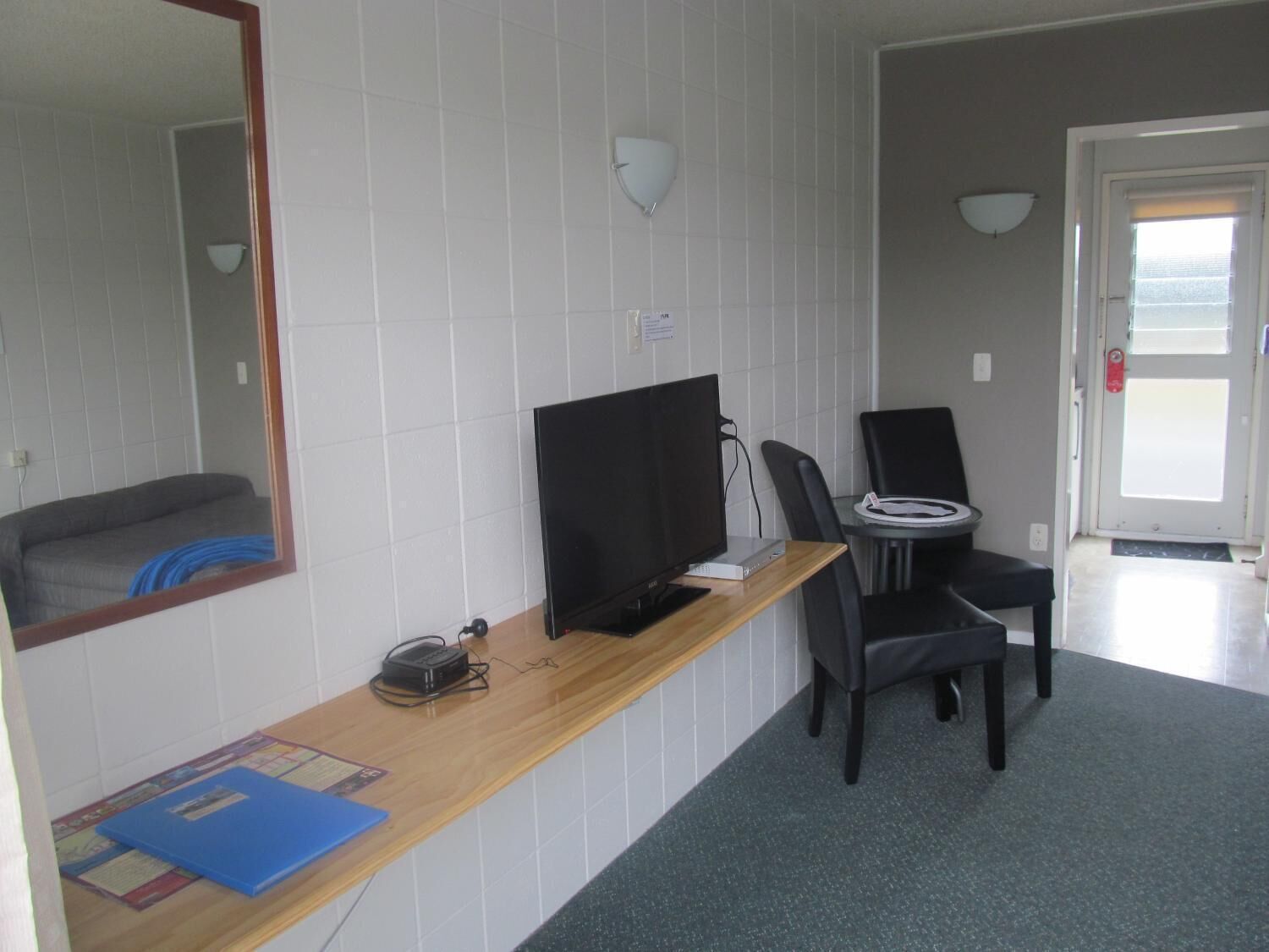 Habitación de hotel con un escritorio de madera, una computadora, una silla y un espejo grande.