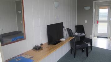 Habitación de hotel con un escritorio de madera, una computadora, una silla y un espejo grande.