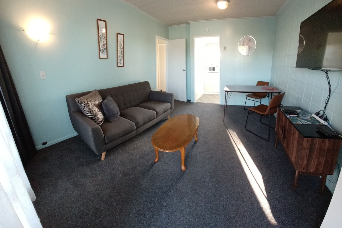 A living room with a sofa, coffee table, and dining area with chairs and a small table.