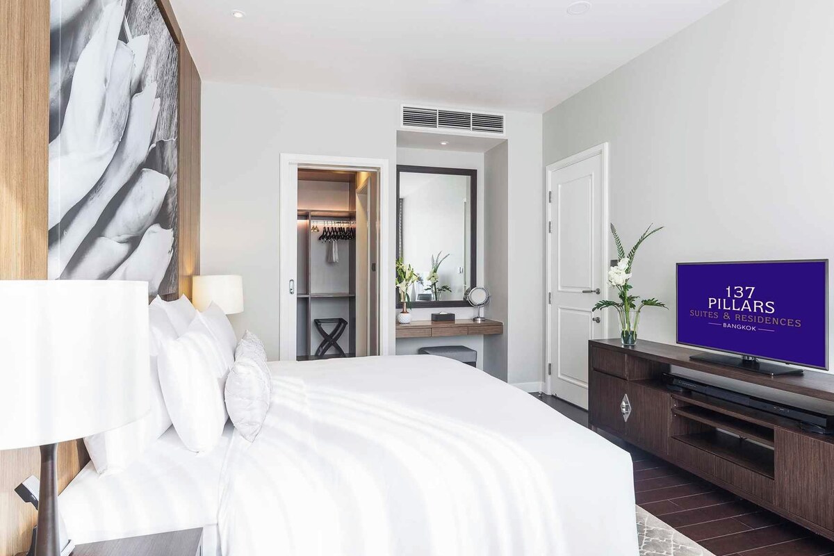 Une chambre d’hôtel avec un lit, une télévision, une armoire et un miroir.