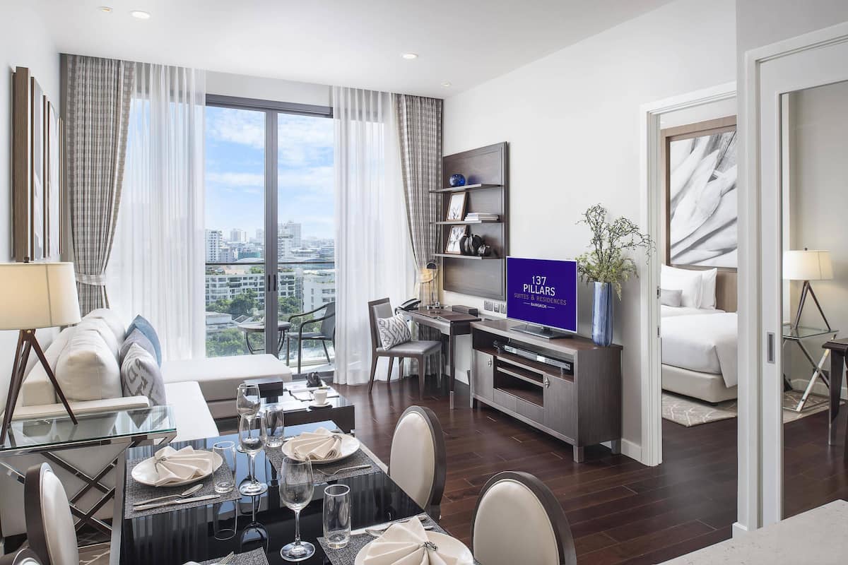 Een moderne hotelkamer met een eetgedeelte, een zithoek en een groot raam met uitzicht op de stad.
