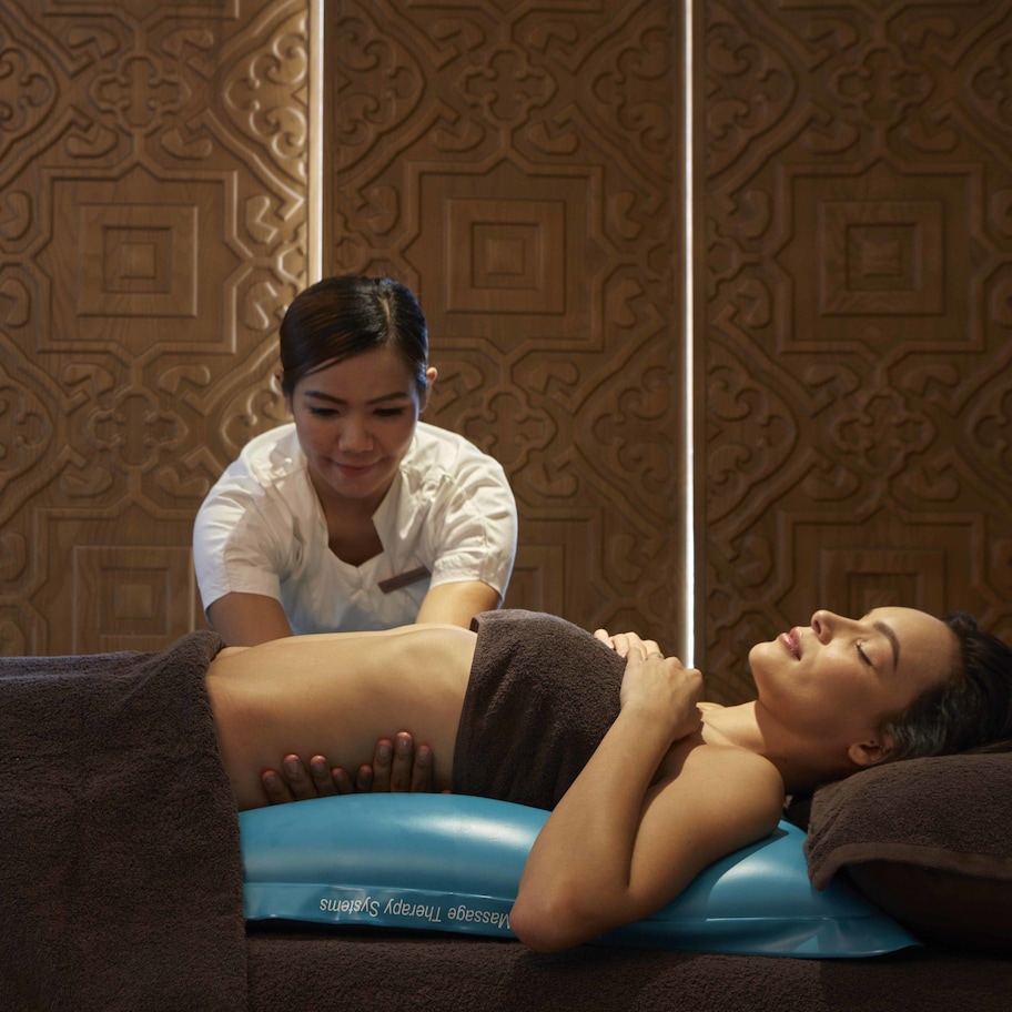 A massage therapy session in a room with patterned wooden paneling.