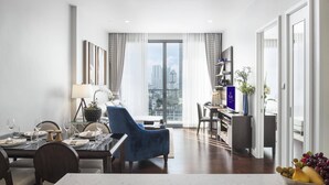 Un salon moderne comprenant un coin repas, un fauteuil bleu, une table à manger et une grande fenêtre avec des rideaux.