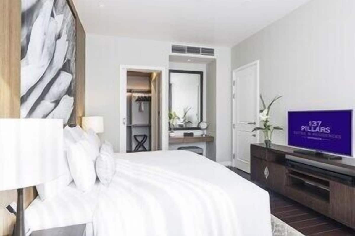 Een moderne hotelkamer met een groot bed, een televisie, een kledingkast en een badkamer zichtbaar door een geopende deur.
