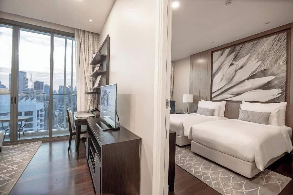 Hotelkamer met uitzicht op de stad, een bureau met stoel, een bed en een groot abstract kunstwerk aan de muur.