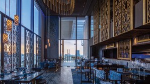 Een modern restaurant met hoge plafonds, grote ramen en gedetailleerd houten lambrisering.