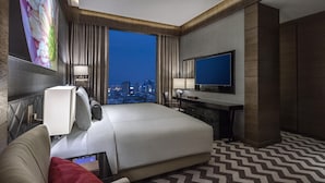 Een moderne hotelkamer met een groot bed, een bureau, een televisie en uitzicht over de stad.