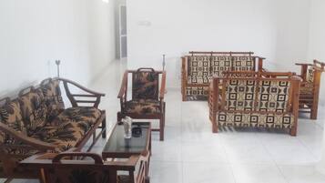 A room with a sofa, chairs, and a table.