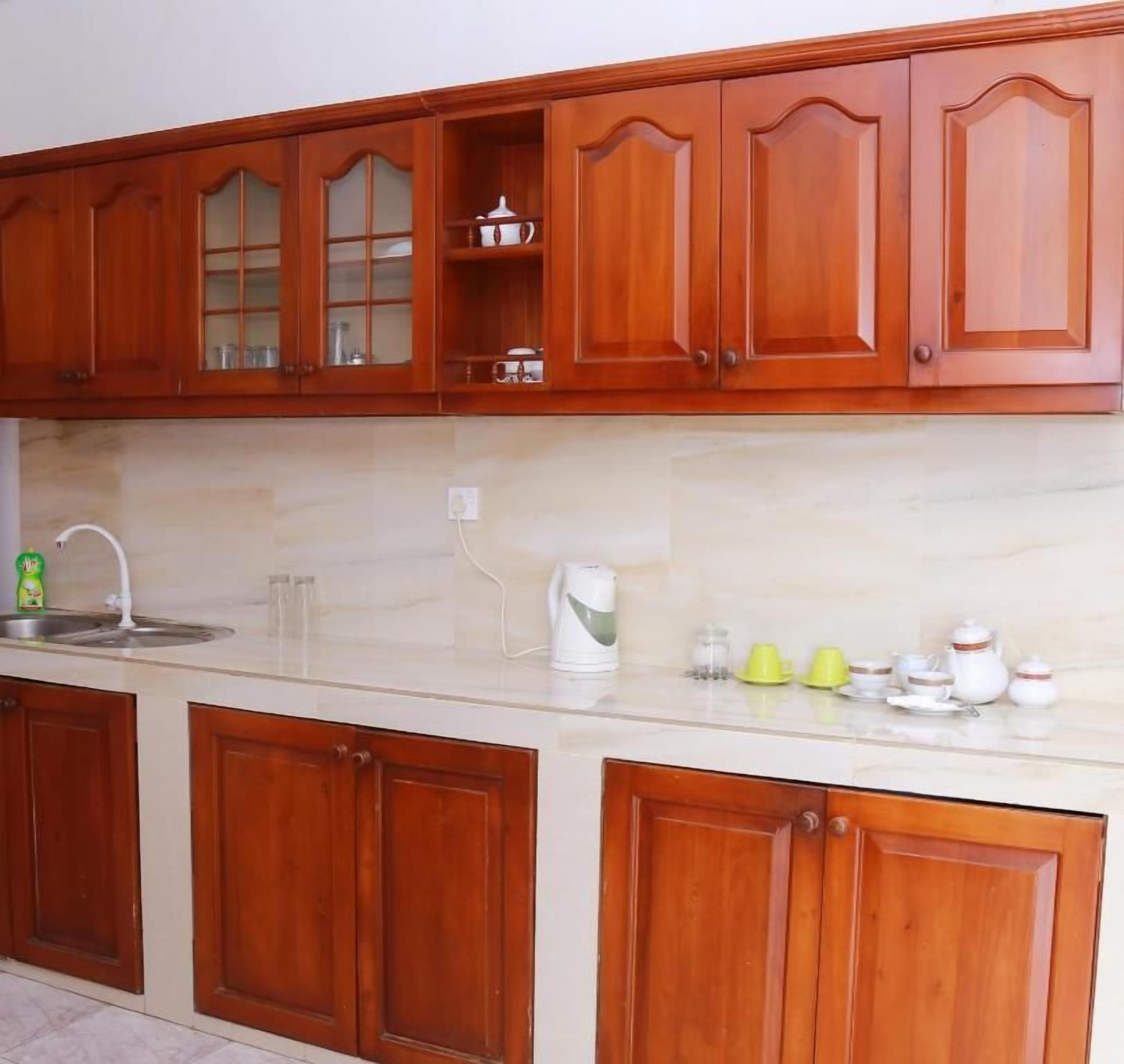 A kitchen with wooden cabinets, a marble countertop, and various kitchen items.