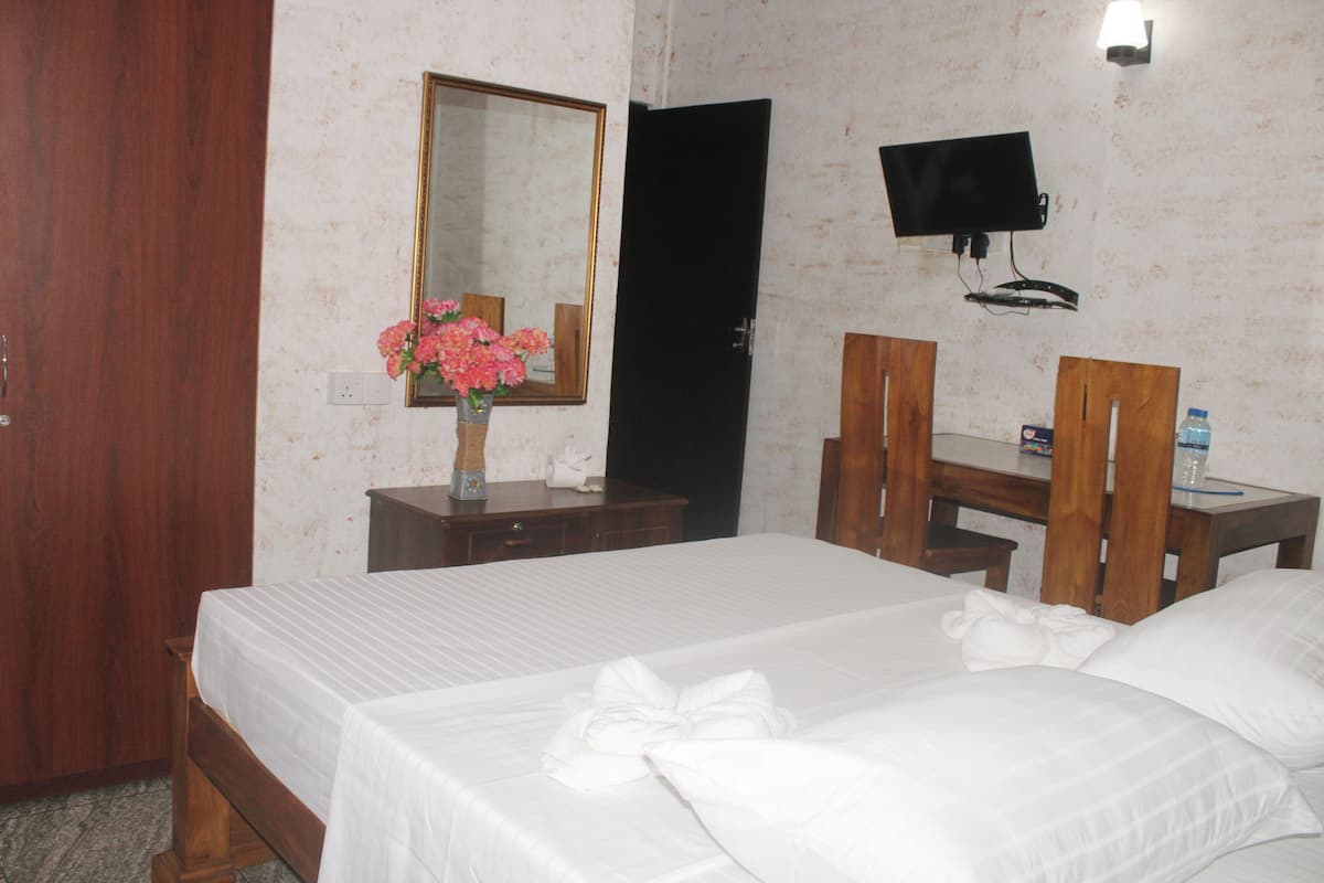 A hotel room with a bed, a desk, a chair, a TV, and a mirror.