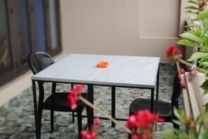 A small outdoor seating area with a marble table and chairs, a potted plant, and a tiled floor. - Villa 142 (Mount Lavinia)