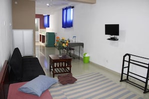 A hotel room with a bed, a small table with flowers, a TV, and a window with curtains. - Villa 142 (Mount Lavinia)