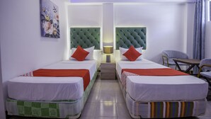 A hotel room with two beds, a nightstand, a lamp, a chair, and a painting on the wall. - OYO 725 Richdel Resort Hotel (Lapu-Lapu)