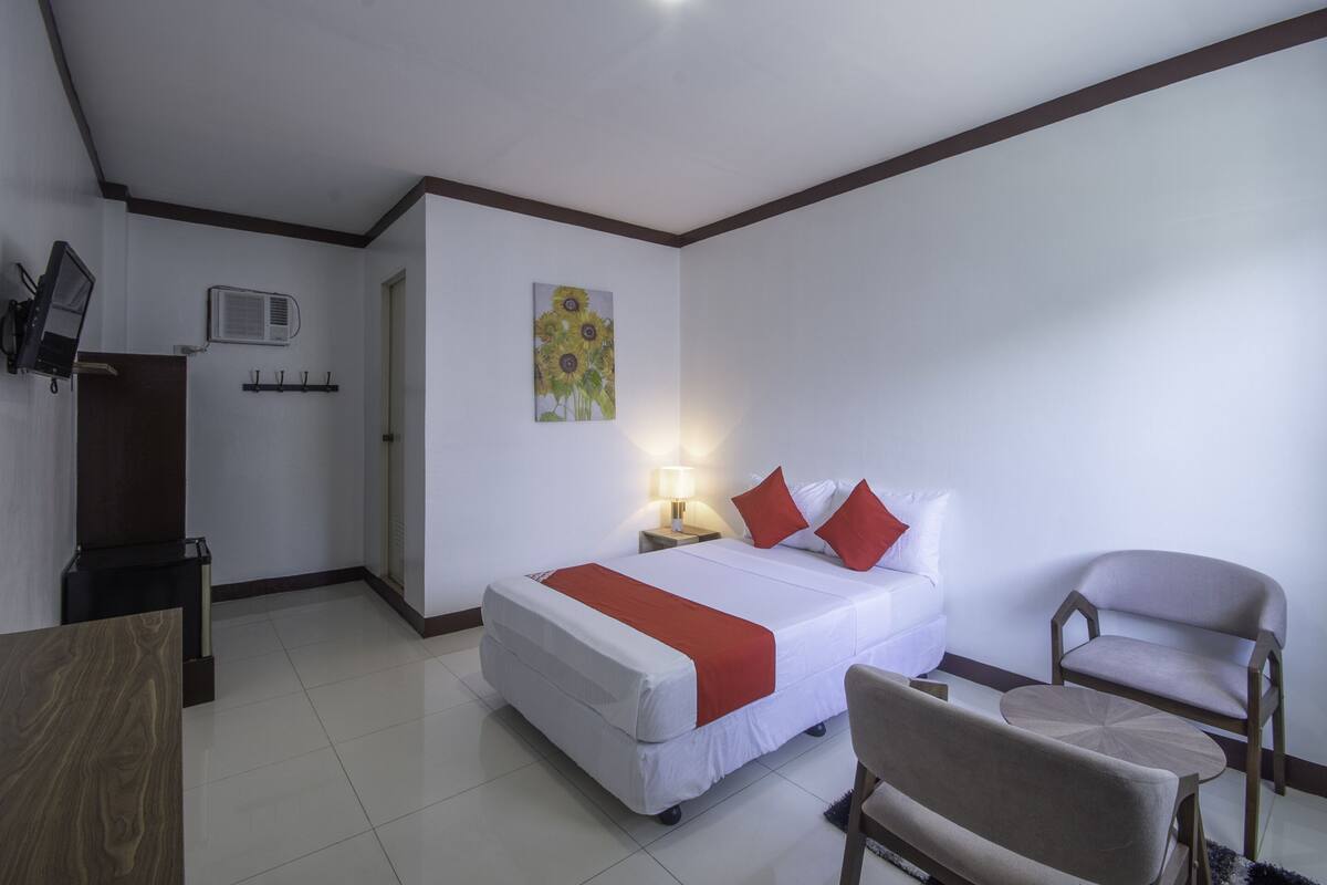 Une chambre d’hôtel avec un lit, une chaise, un bureau, une lampe et un tableau au mur.