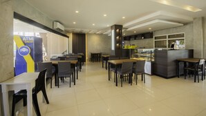 A modern cafe with tables and chairs, an ATM, and a counter with a display case. - OYO 725 Richdel Resort Hotel (Lapu-Lapu)