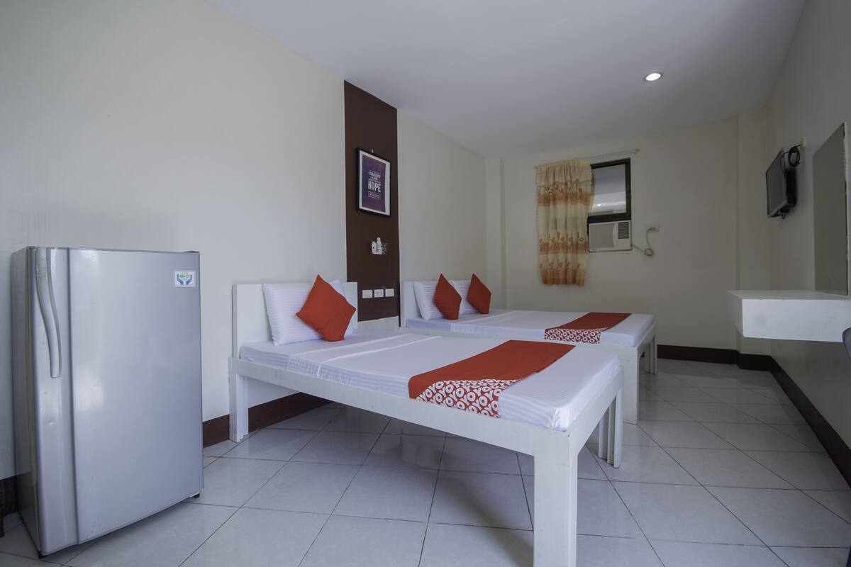 Une chambre d’hôtel avec deux lits, un réfrigérateur, une salle de bain et un téléviseur.