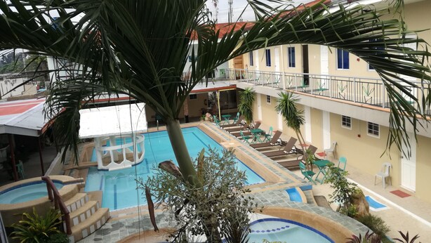 A pool area with multiple levels, palm trees, and lounge chairs. - OYO 725 Richdel Resort Hotel (Lapu-Lapu)