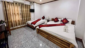 A hotel room with two beds, a television, a ceiling fan, and a window with curtains. - Nocknoy Lanexang Guesthouse (Luang Prabang)