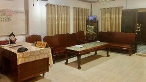 A living room with a sofa set, a coffee table, a TV, and a reception area. - Nocknoy Lanexang Guesthouse (Luang Prabang)