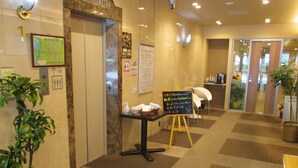 A hotel lobby with a reception desk, a map on the wall, and a signboard with information. - Hotel Green With (Sendai)