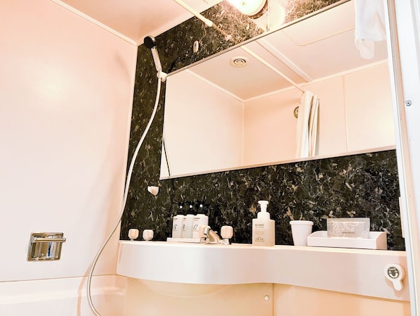 Un baño con tocador blanco, salpicadero de mármol negro y artículos de aseo en la encimera.