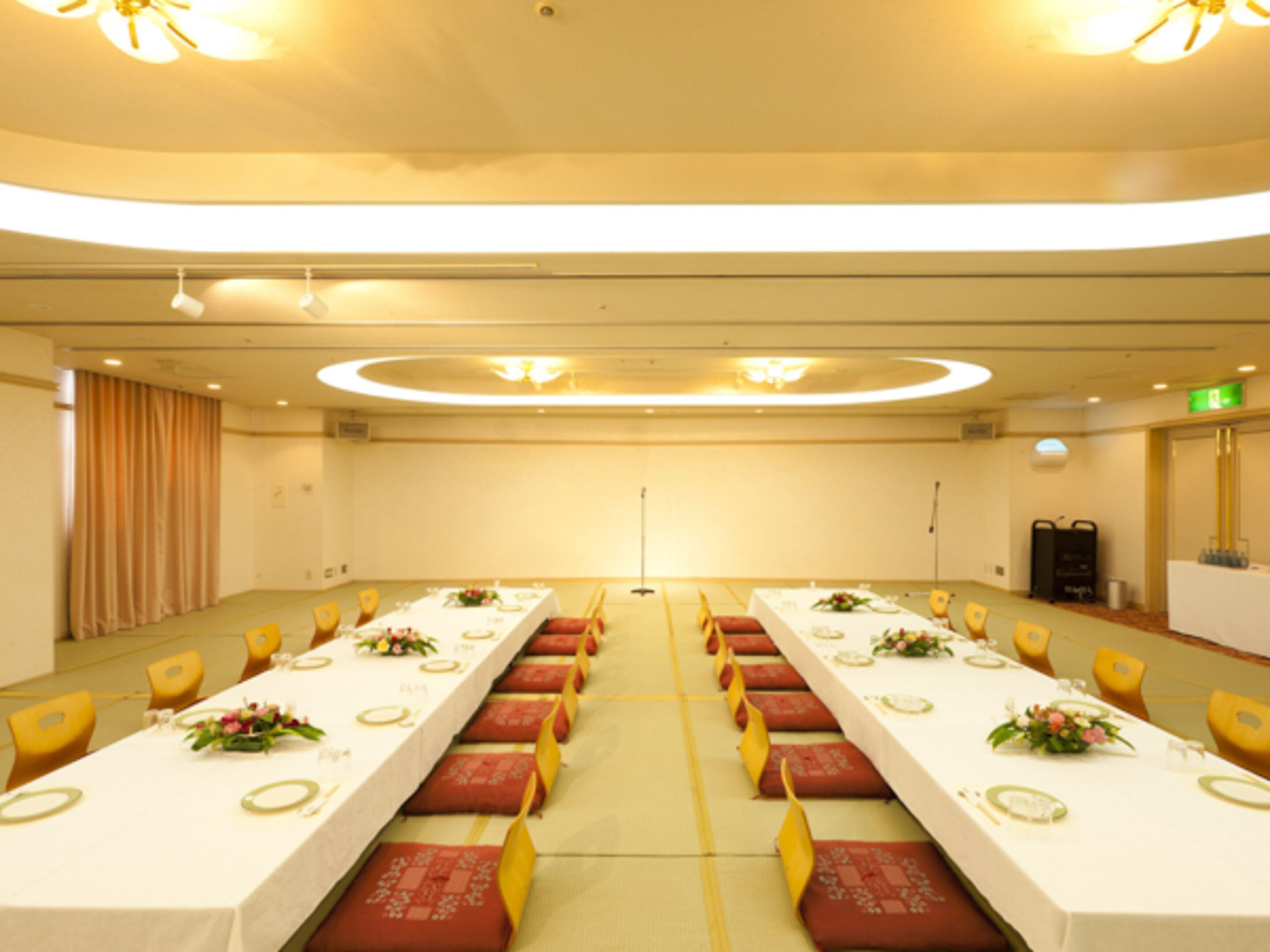 A conference room with long tables, yellow chairs, and a chandelier.