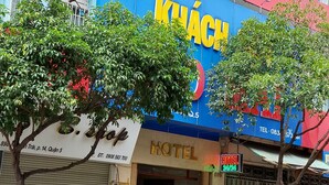 A building with a blue and red facade, a visible sign for 'HOTEL', and a tree in front.