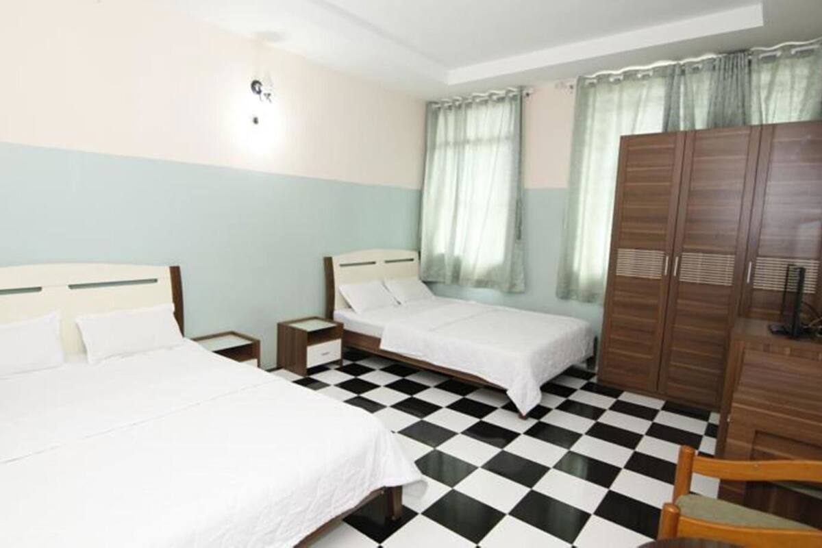 Habitació d'hotel amb dos llits, un terra de pissos, un armari i una taula petita.