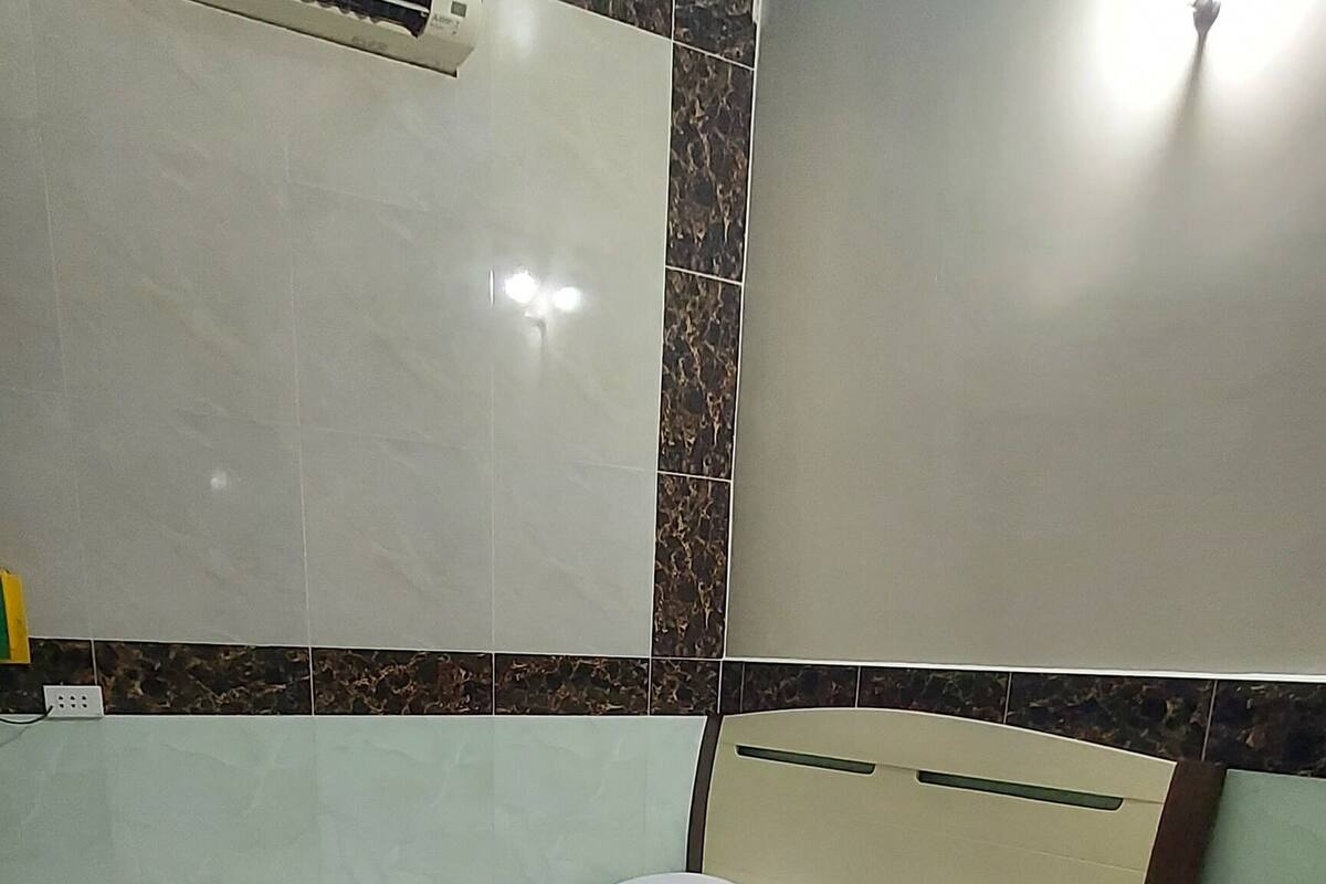 Habitació amb un llit, una tauleta de nit, aire condicionat fixat a la paret i un paviment amb quadres.