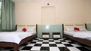 A room with two beds, a checkered floor, and a light-colored wall.