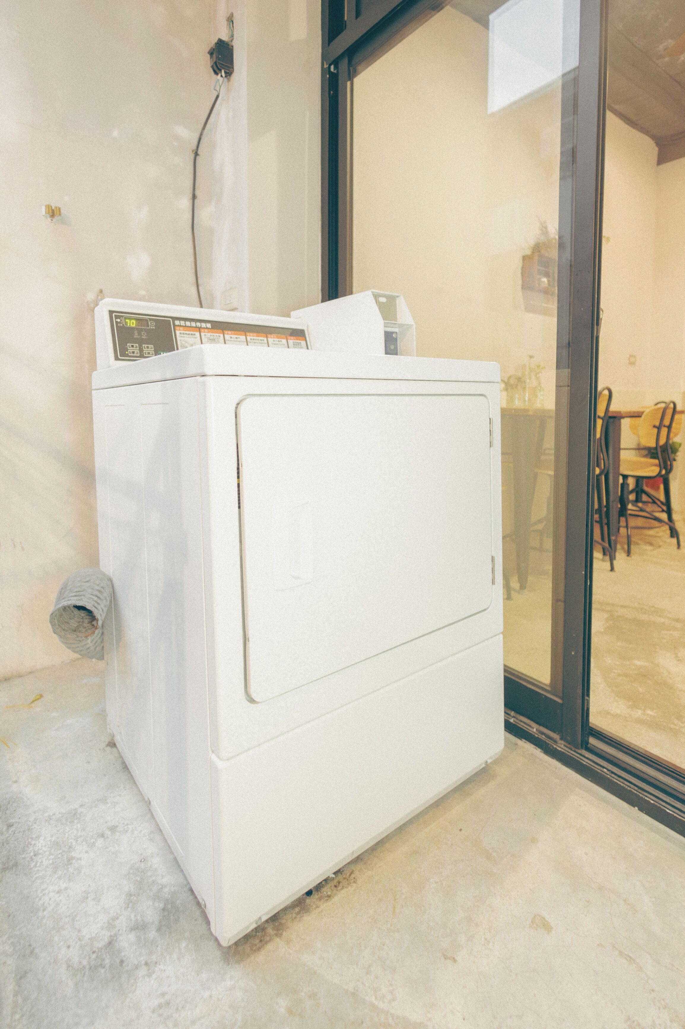 A white washing machine in a room with a glass door leading to an outdoor area.