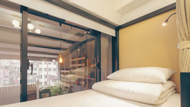 A modern bedroom with a bed, a sliding glass door, and a view of buildings outside. - DONGMEN 3 Capsule Inn - Hostel (Taipei)